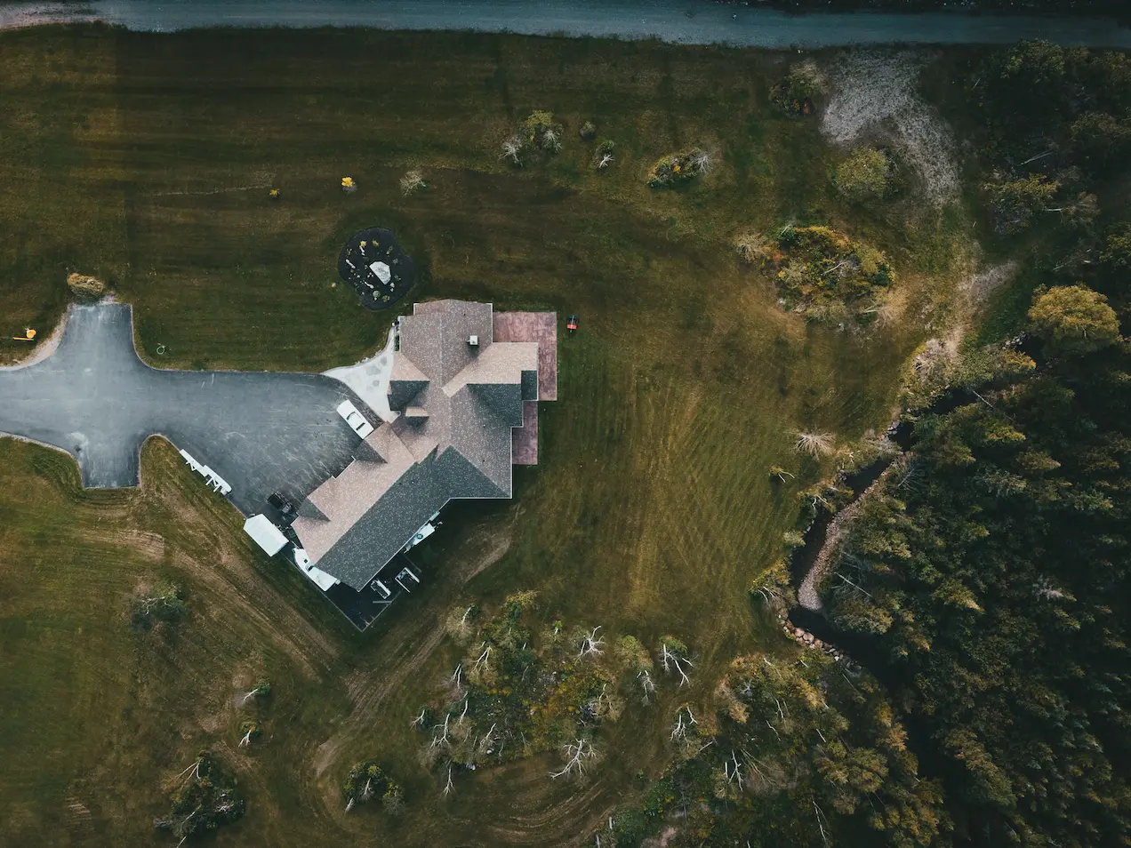 Vue aérienne d'une maison entourée de verdure et d'une allée