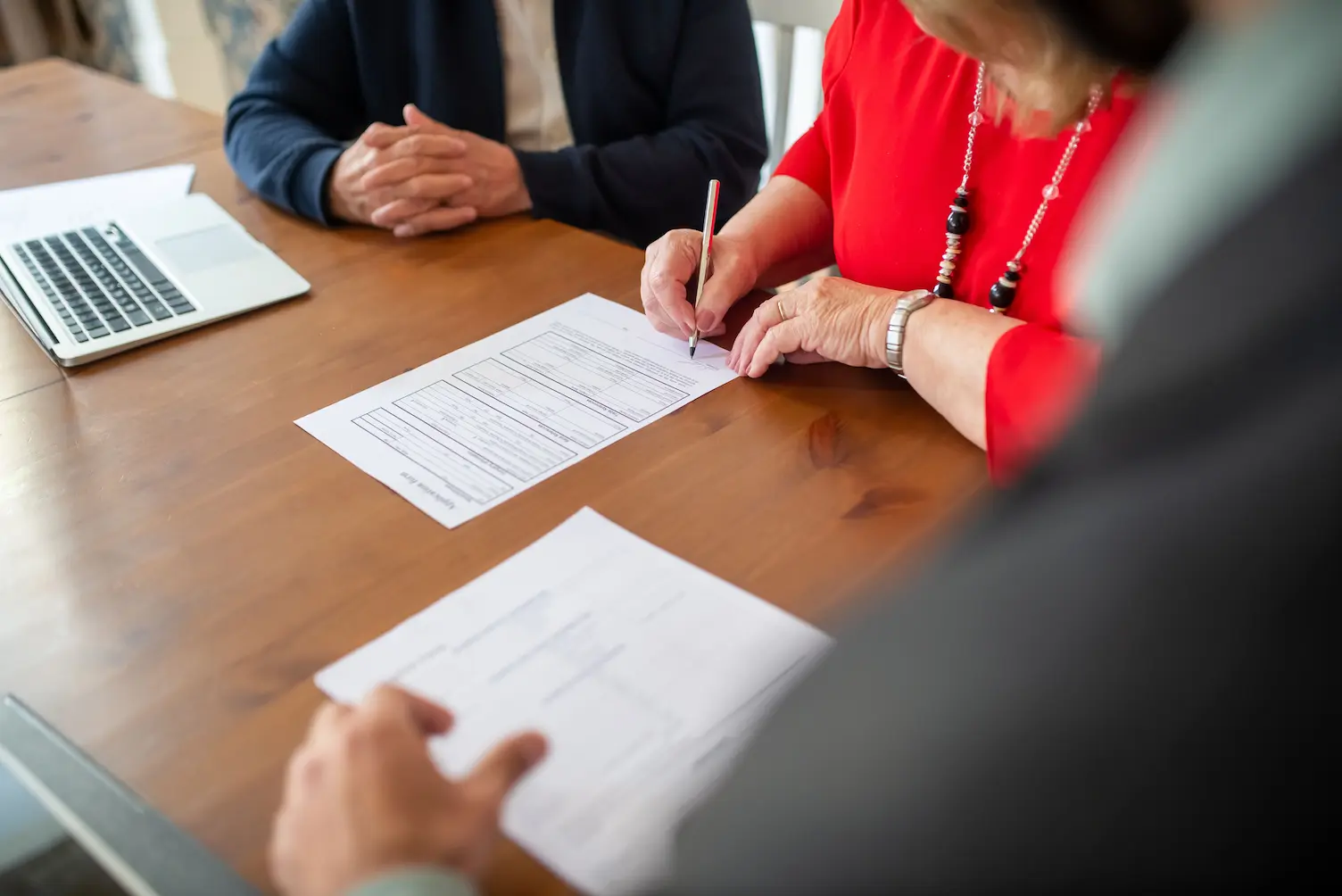 Deux adultes signent des documents sur une table en boi
