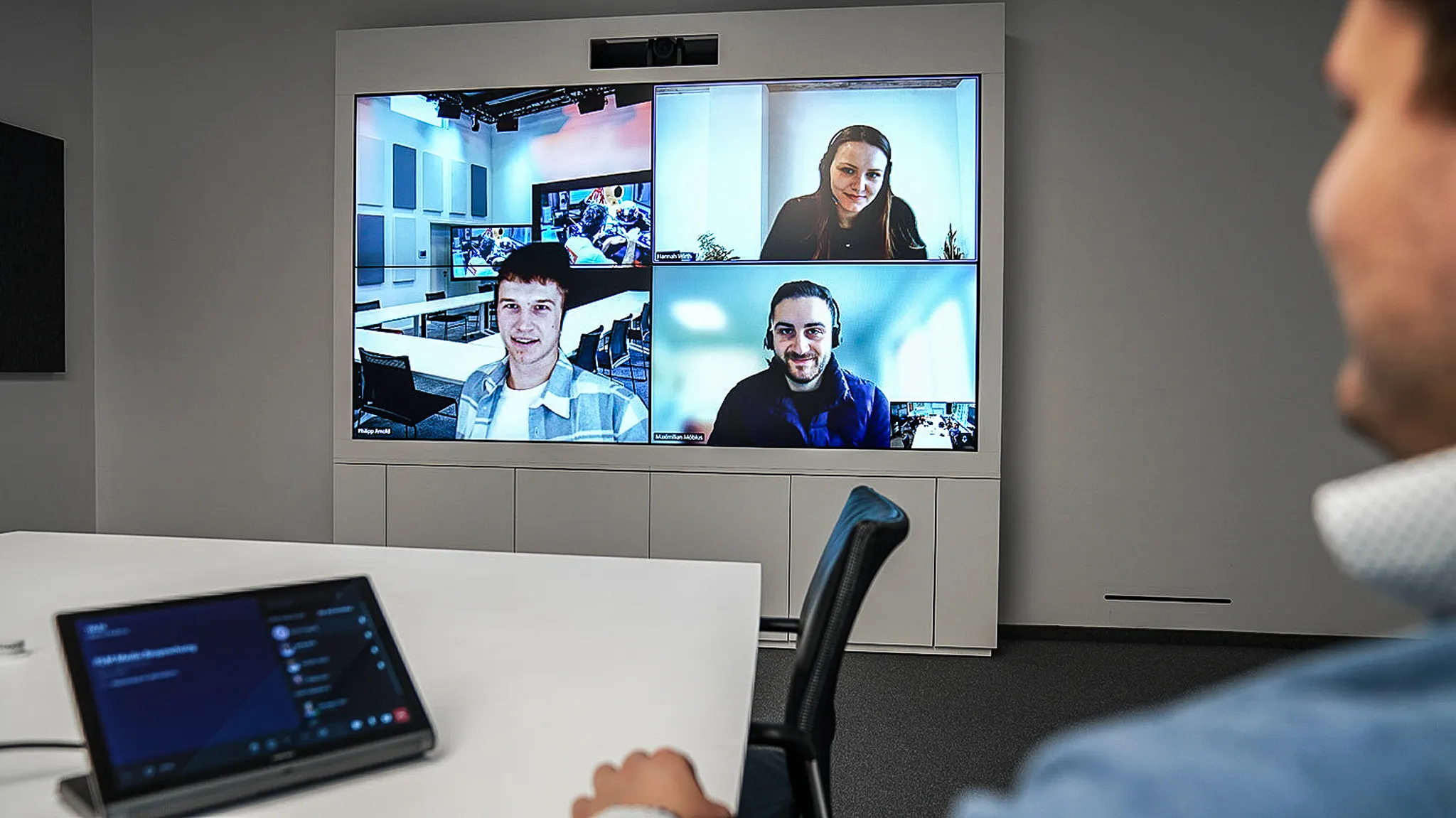 Ein Mann, der in einem modernen Besprechungsraum eine Videokonferenz mit seinen Kollegen abhält.