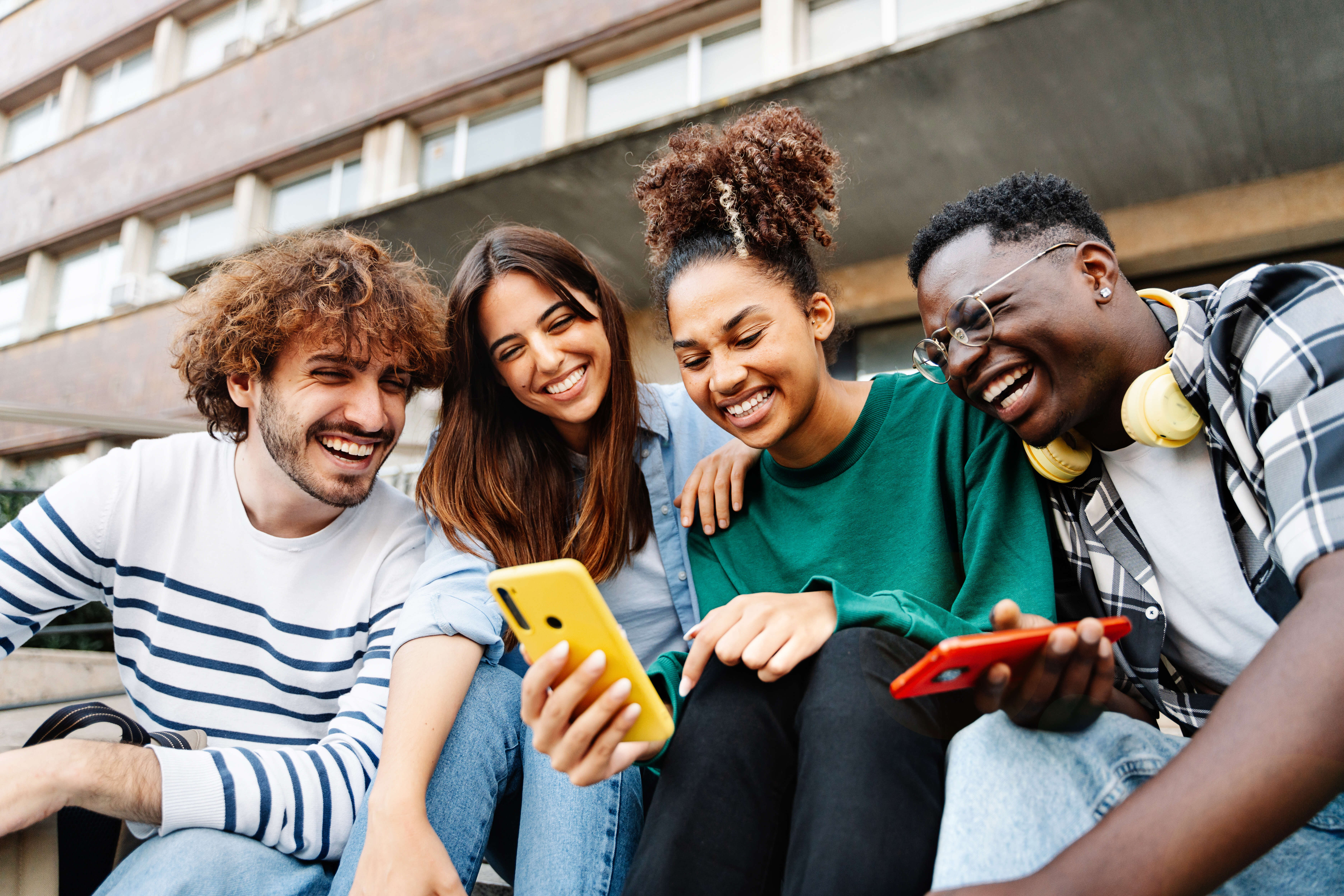 Group of happy friends looking at phone together