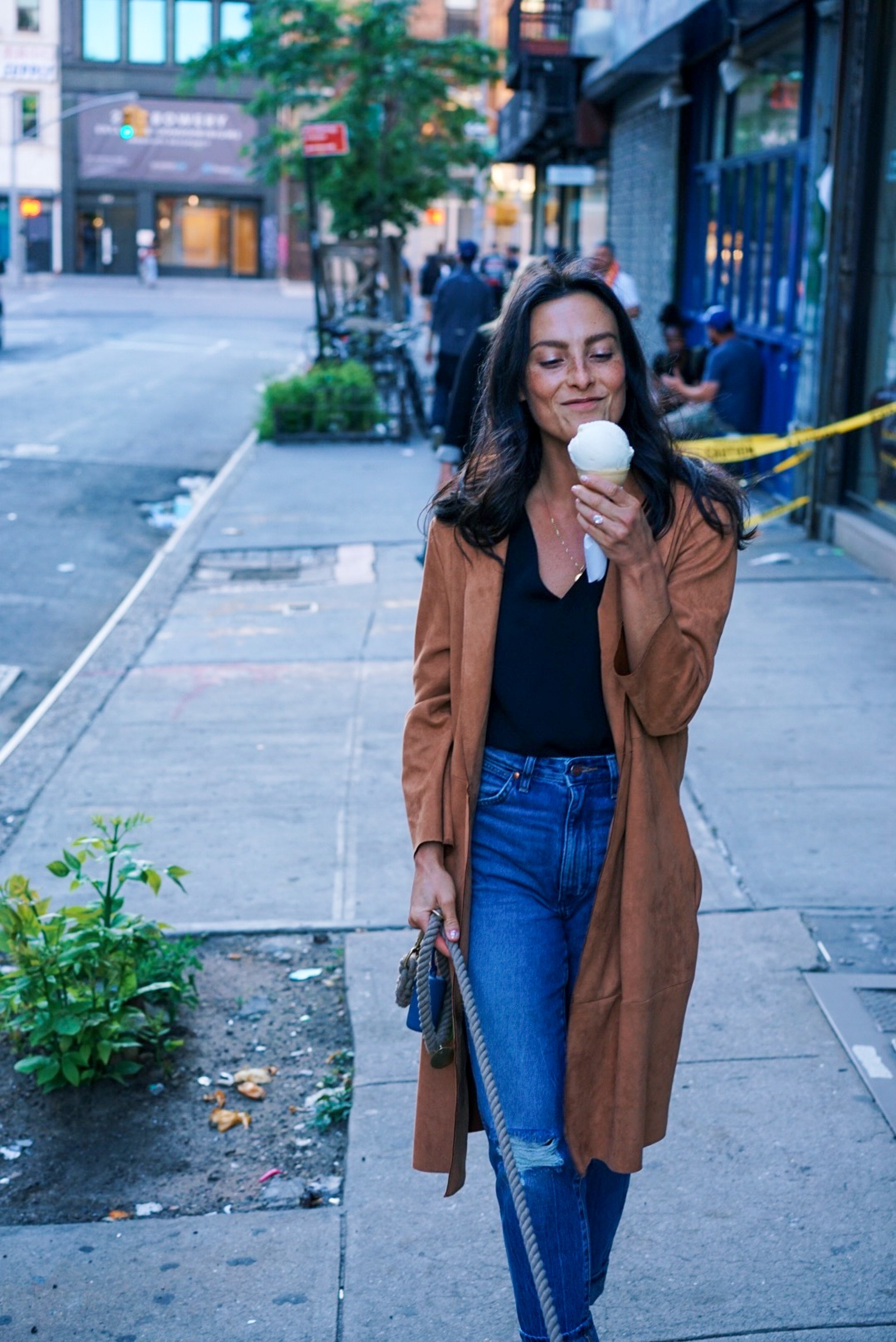 Woman walking down sidewalk eating an ice cream
