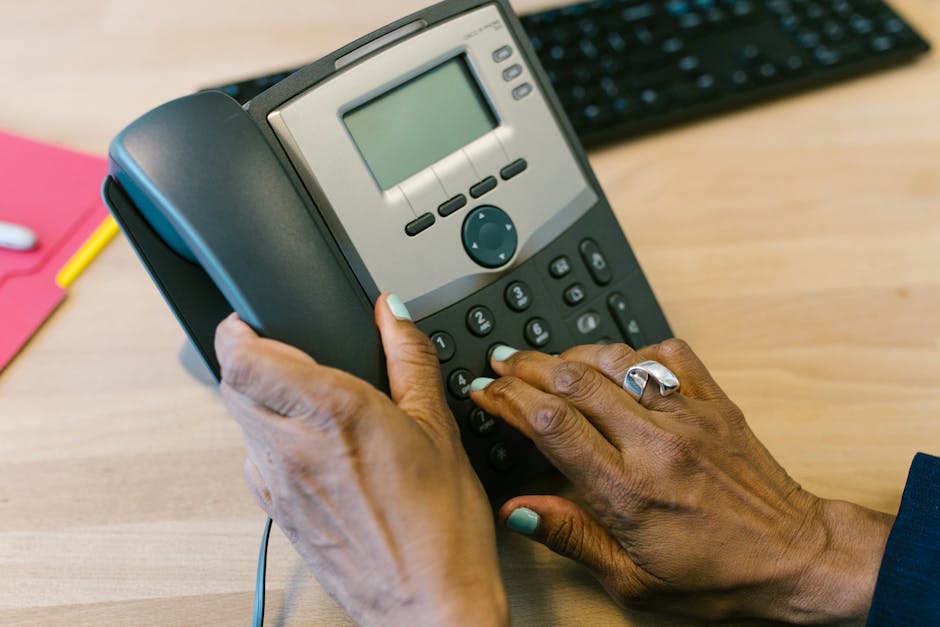 An image of a smartphone displaying a business call interface, alongside traditional landline equipment, showcasing the transition in communication technology.