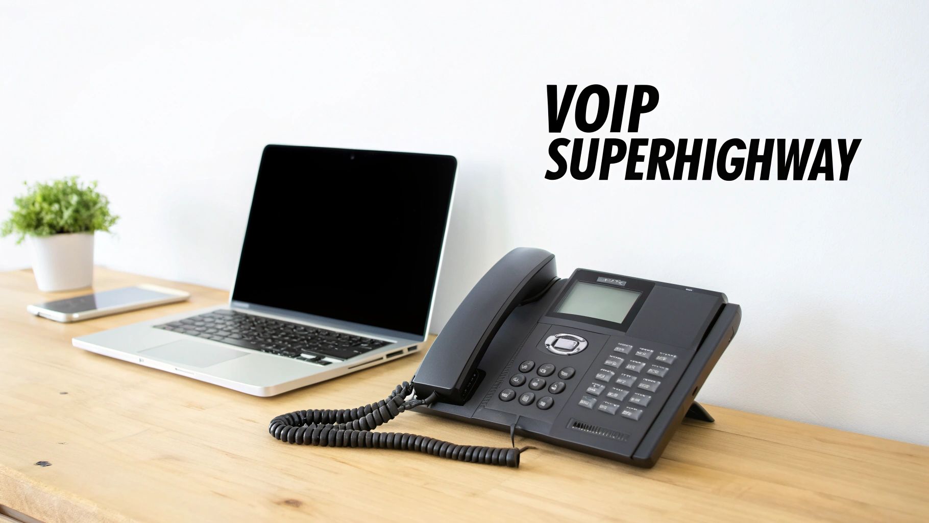 A modern office desk setup featuring a laptop, smartphone, and a black VoIP phone for internet communication.