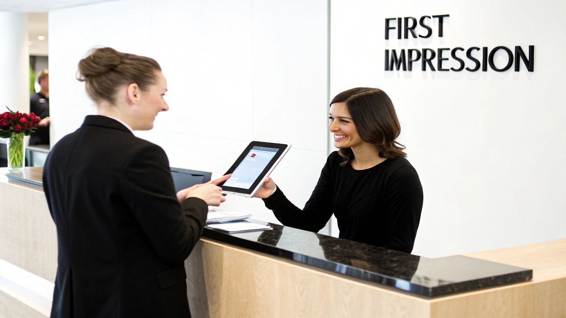 Two women at a reception desk, one filling out a digital customer intake form on a tablet.