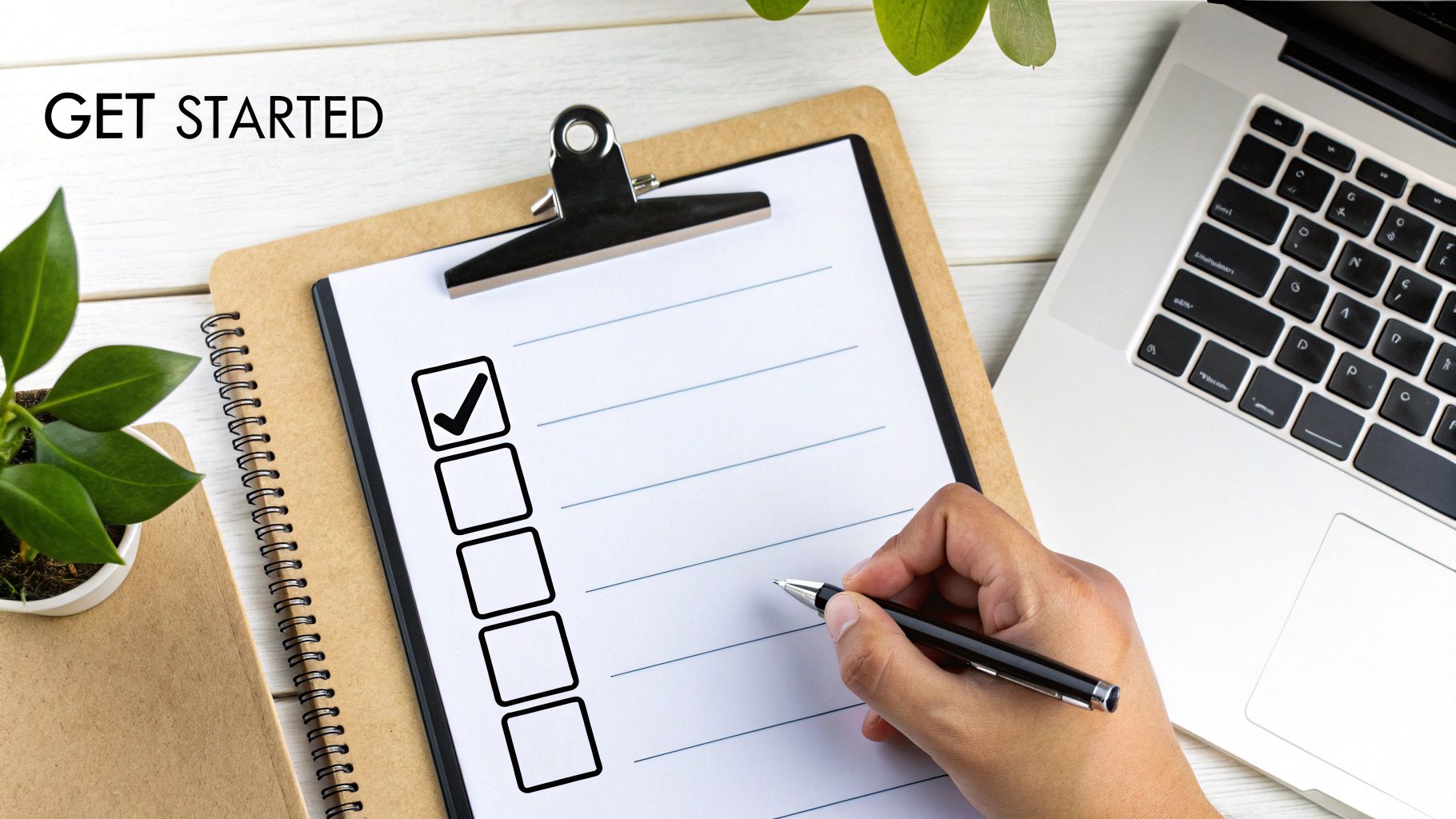 A hand with a pen over a checklist board with 'GET STARTED' text, next to a laptop.