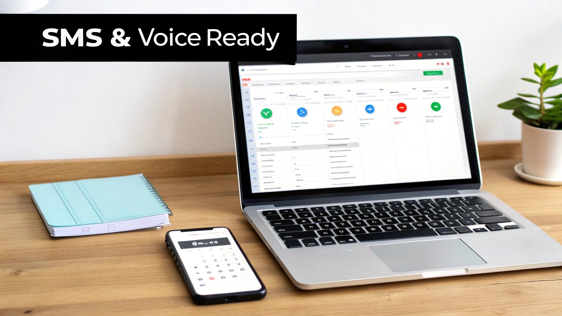 A laptop, smartphone, and notebook on a wooden desk, displaying 'SMS & Voice Ready' text.