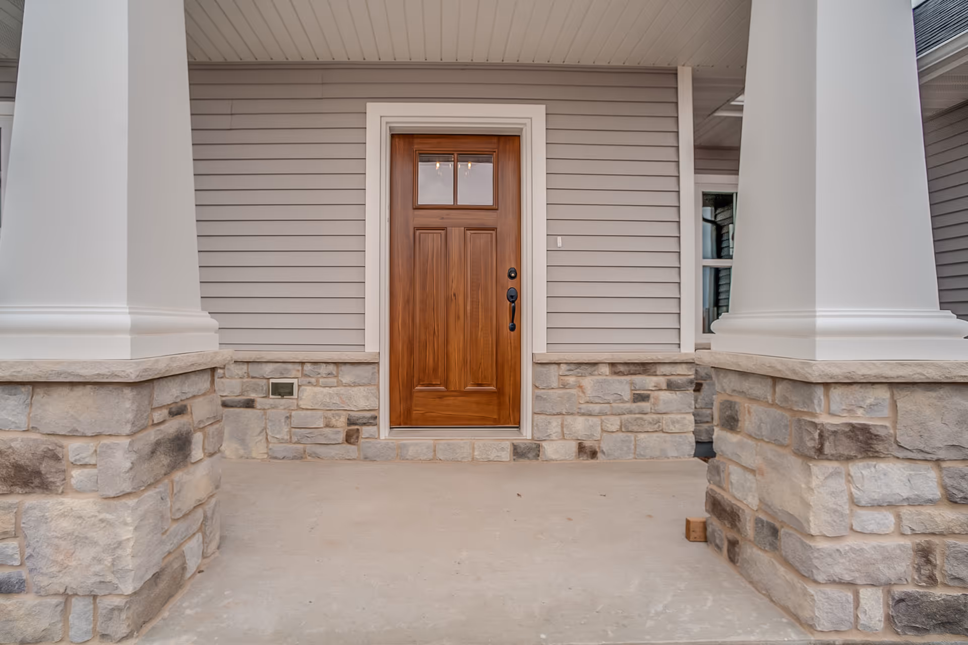 An exterior wood door (with a glass insert) at the entryway of a modern home.
