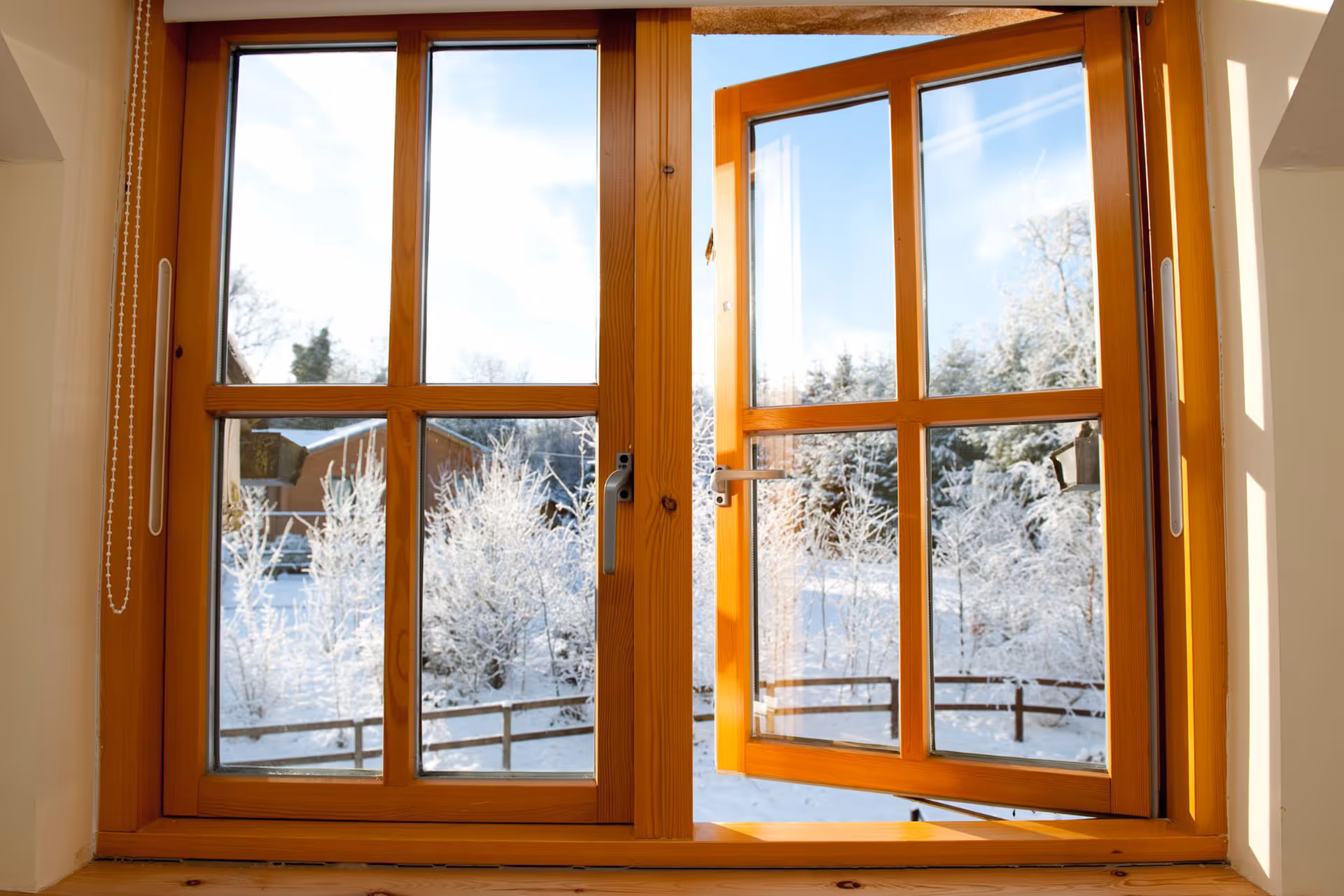 Double paneled wooden casement windows with one open, showing a winter backdrop