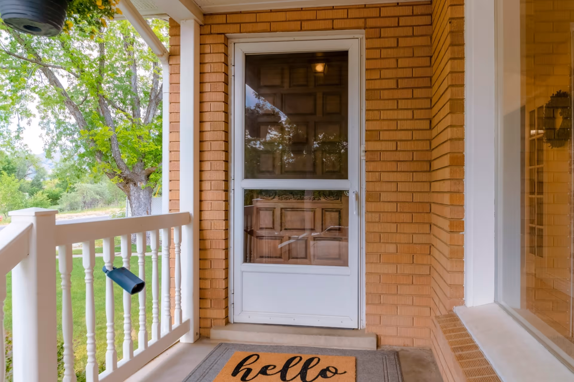 A home with a white mid-view storm door with a retractable screen panel covering a wooden main entry door