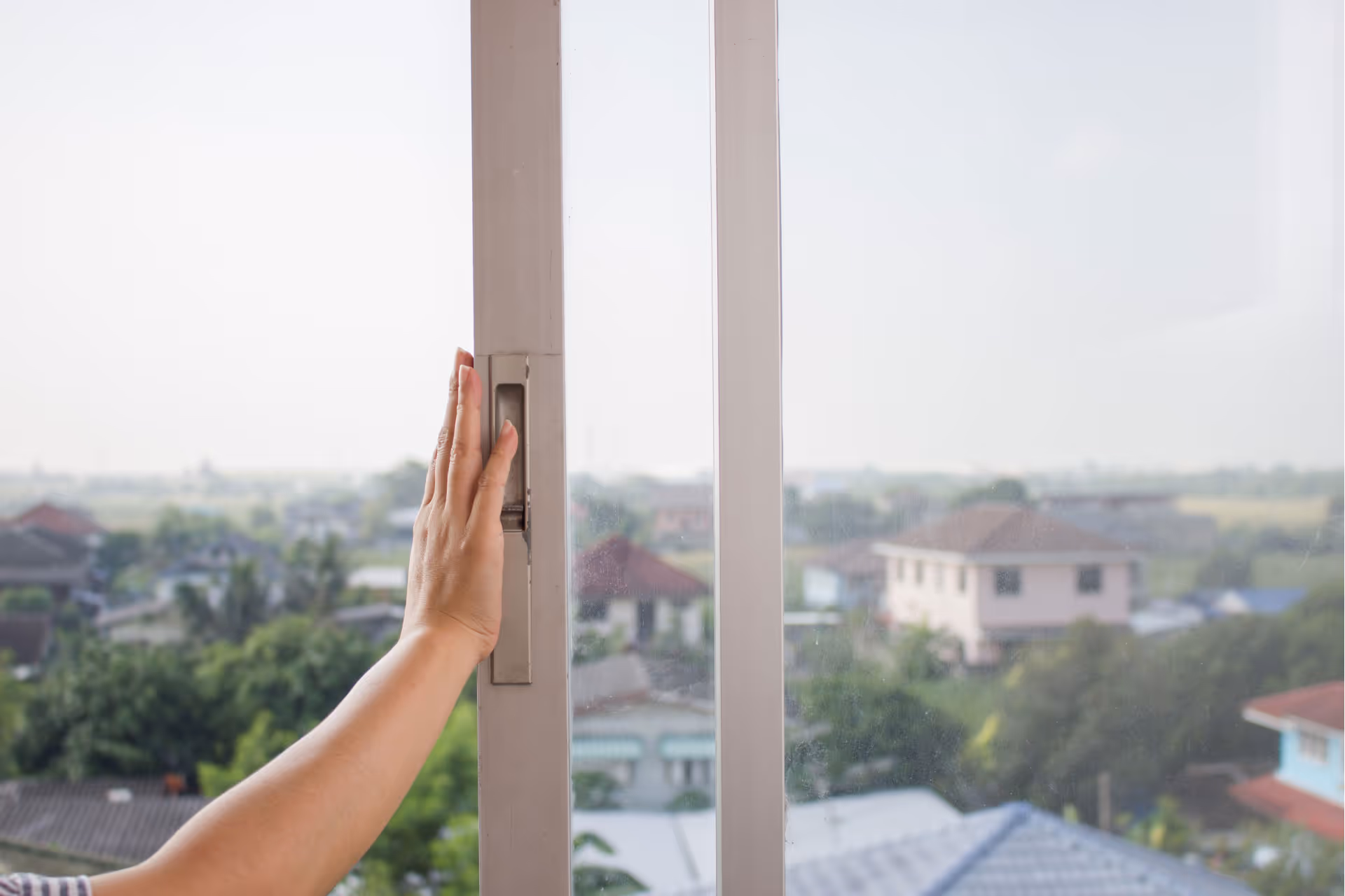 Person opening a slider window with natural light