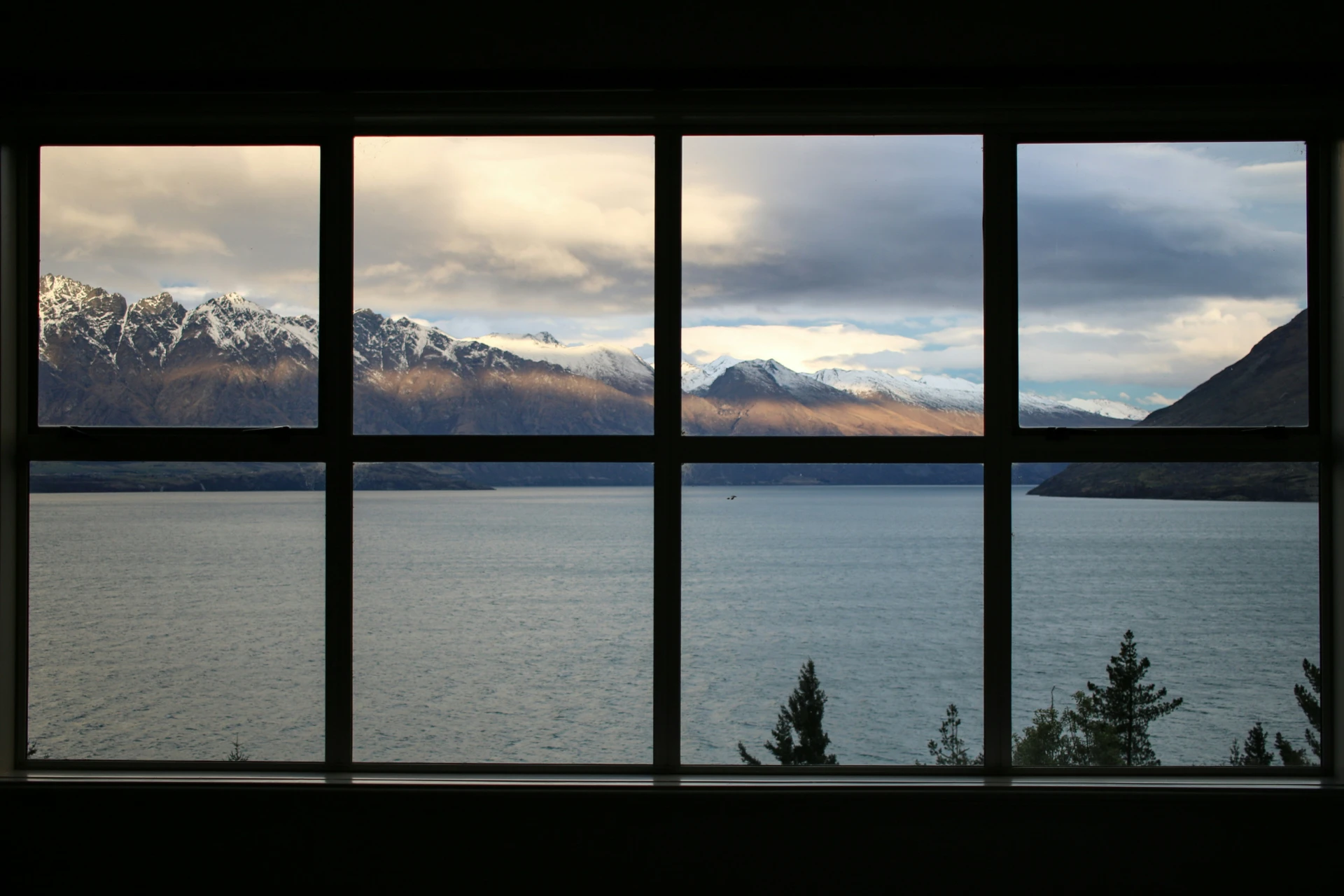 the view of a lake and mountains beyond a window