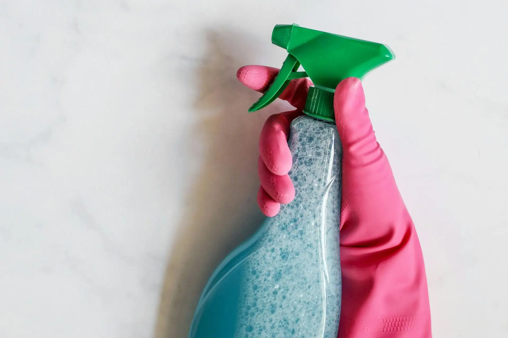 Hands wearing gloves holding cleaning solution