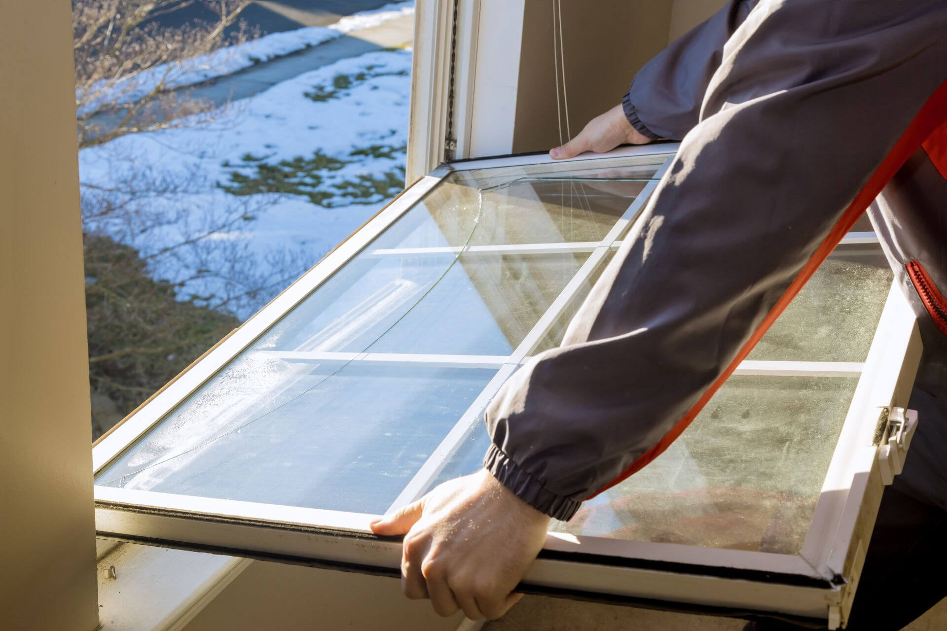 A person removing an old window from the frame