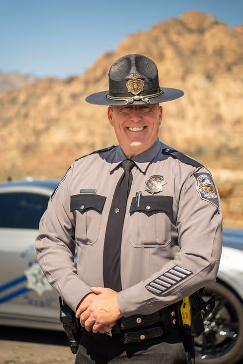 male officer in uniform in front of car