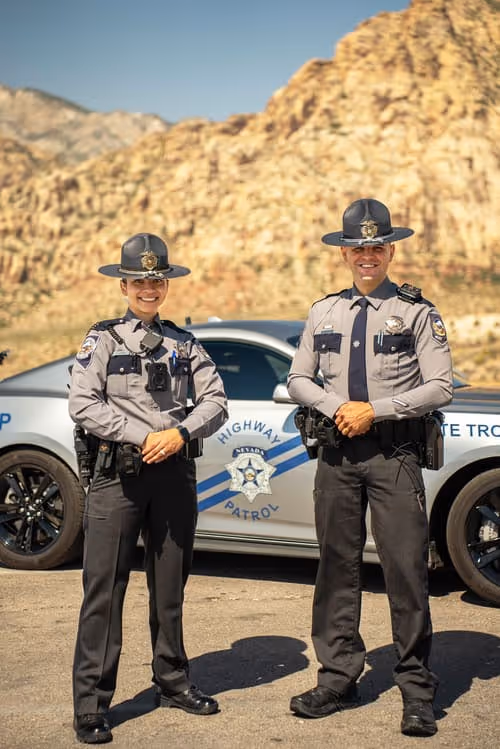 2 officers in uniform in front of police car
