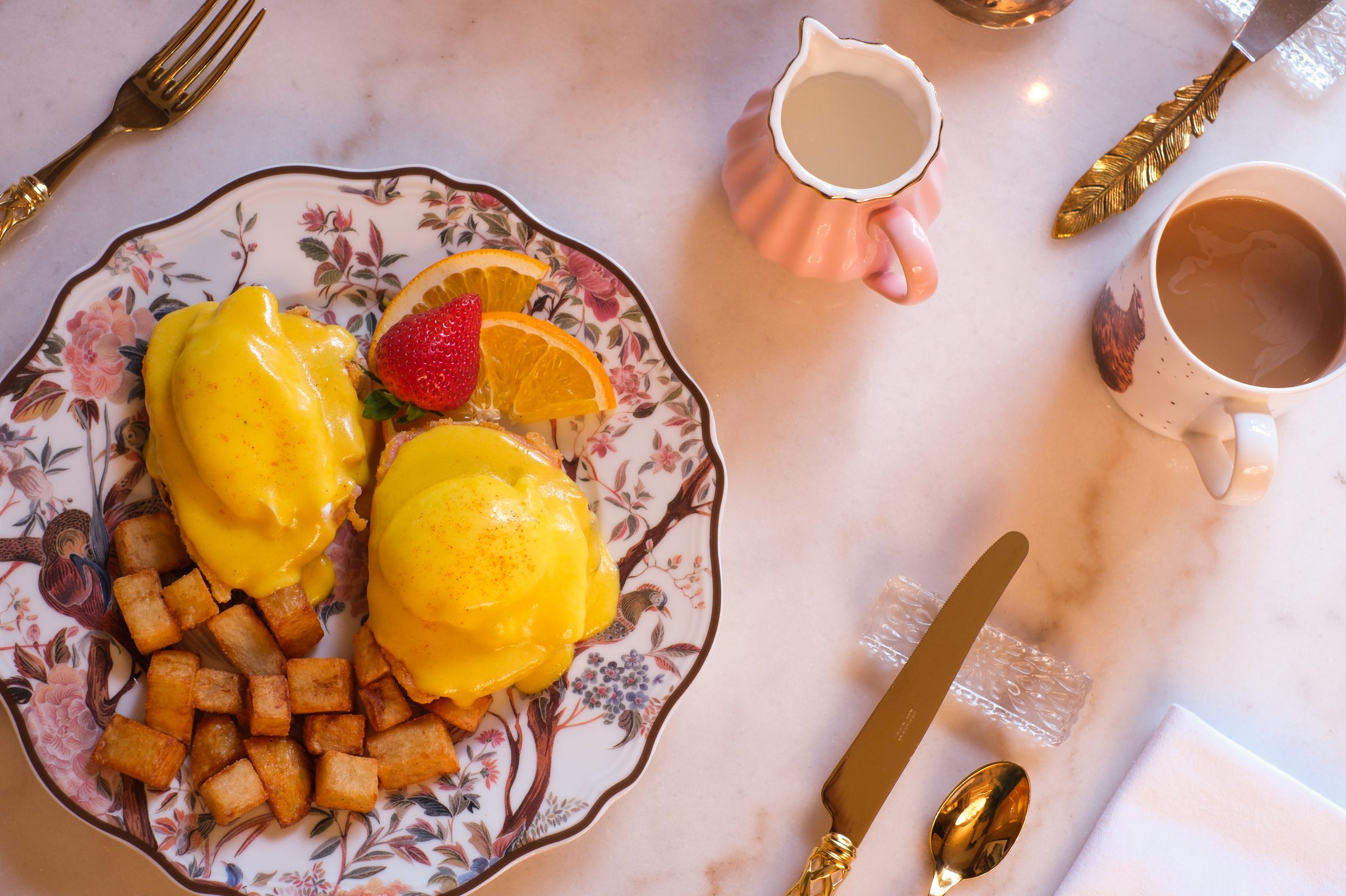 Eggs Benedict with fruit and potatoes on a floral plate at The Scotsman Hotel