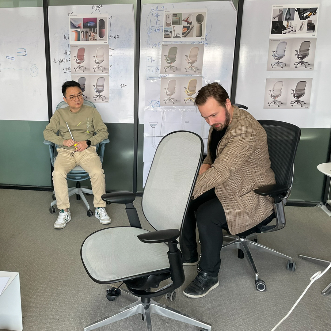 A designer explains a design change on an O2 chair prototype to the engineers at the factory.