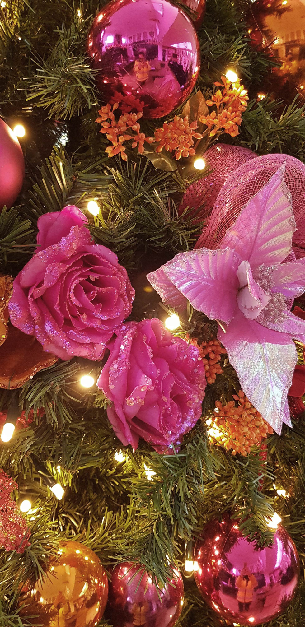 Close-up of pink rose and gold bauble decorations on a Christmas tree