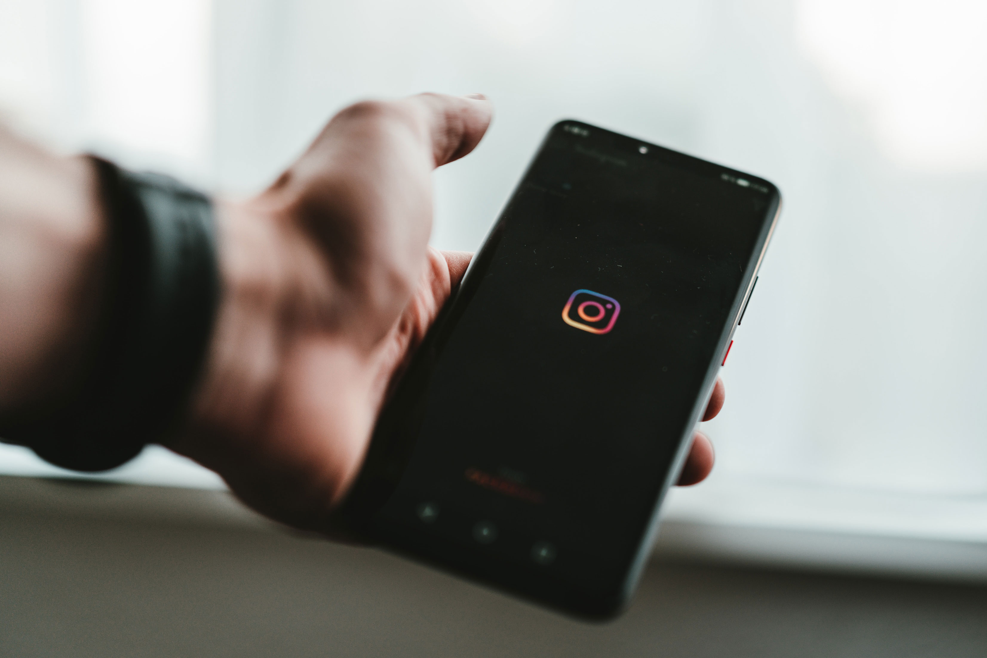 Uma mão segurando um telefone com o aplicativo do Instagram abrindo.