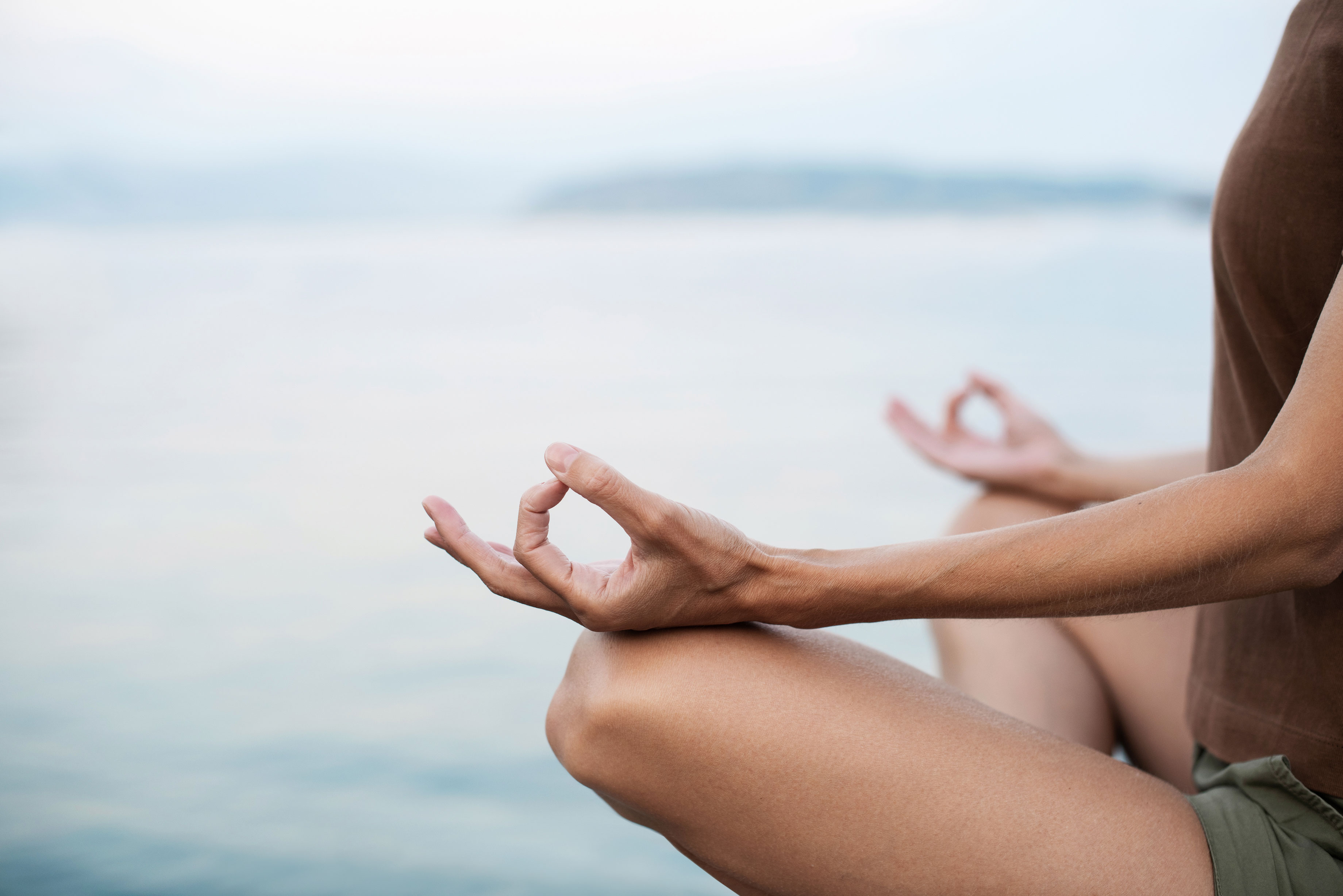 Uma mulher meditando à beira-mar.