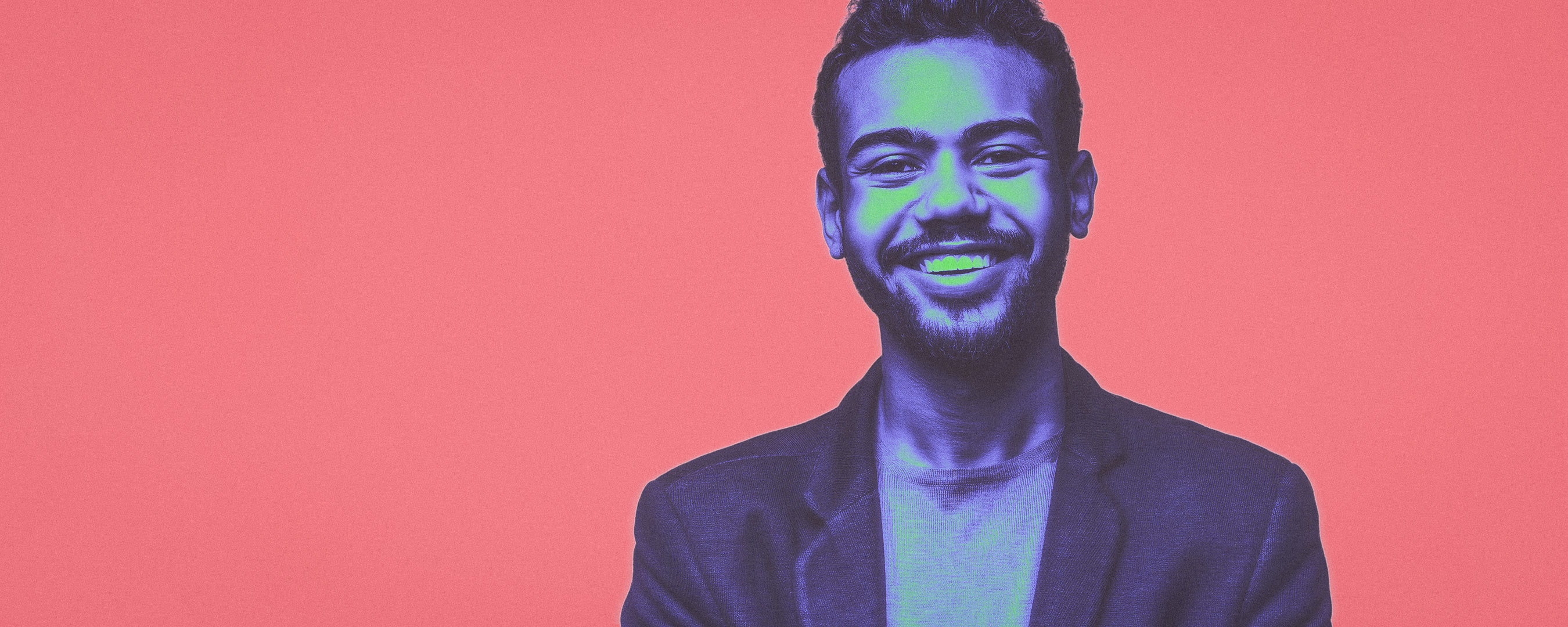 Um homem branco sorrindo em um fundo rosa.