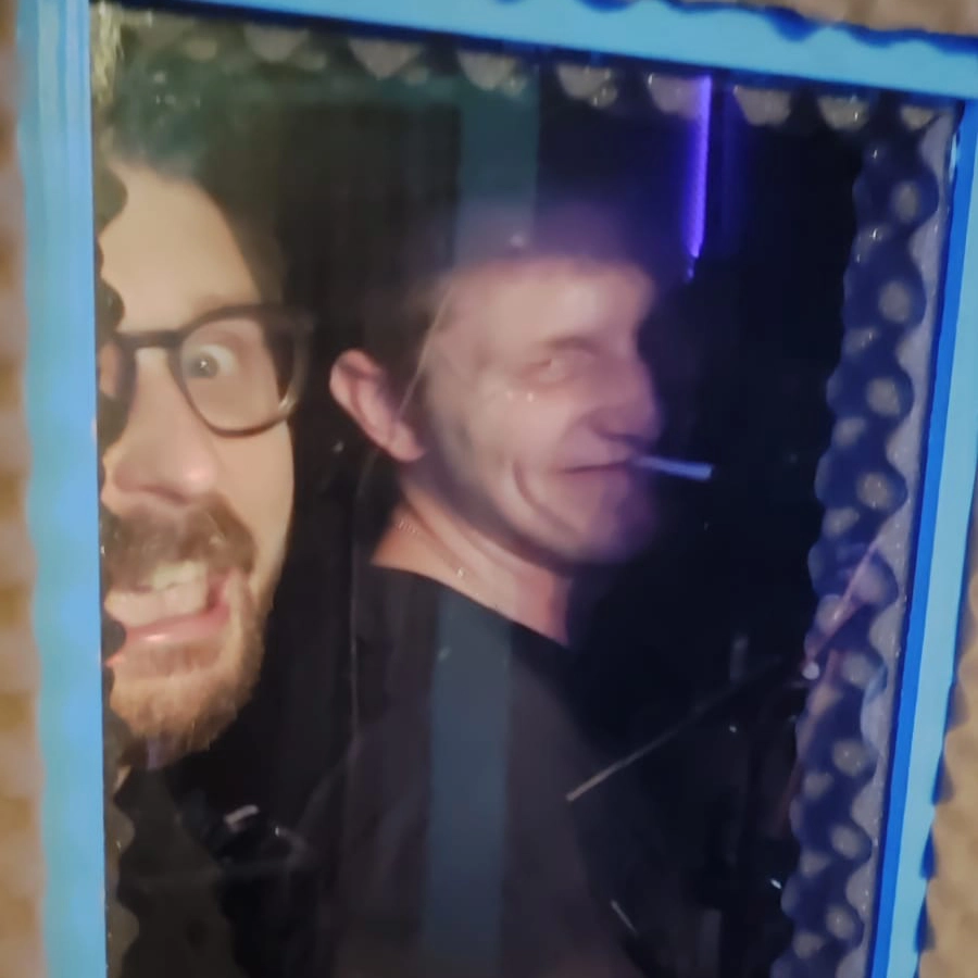 KIP KASPER Mitglieder Andreas und Rafael stehen hinter einer Scheibe und ziehen Grimassen.