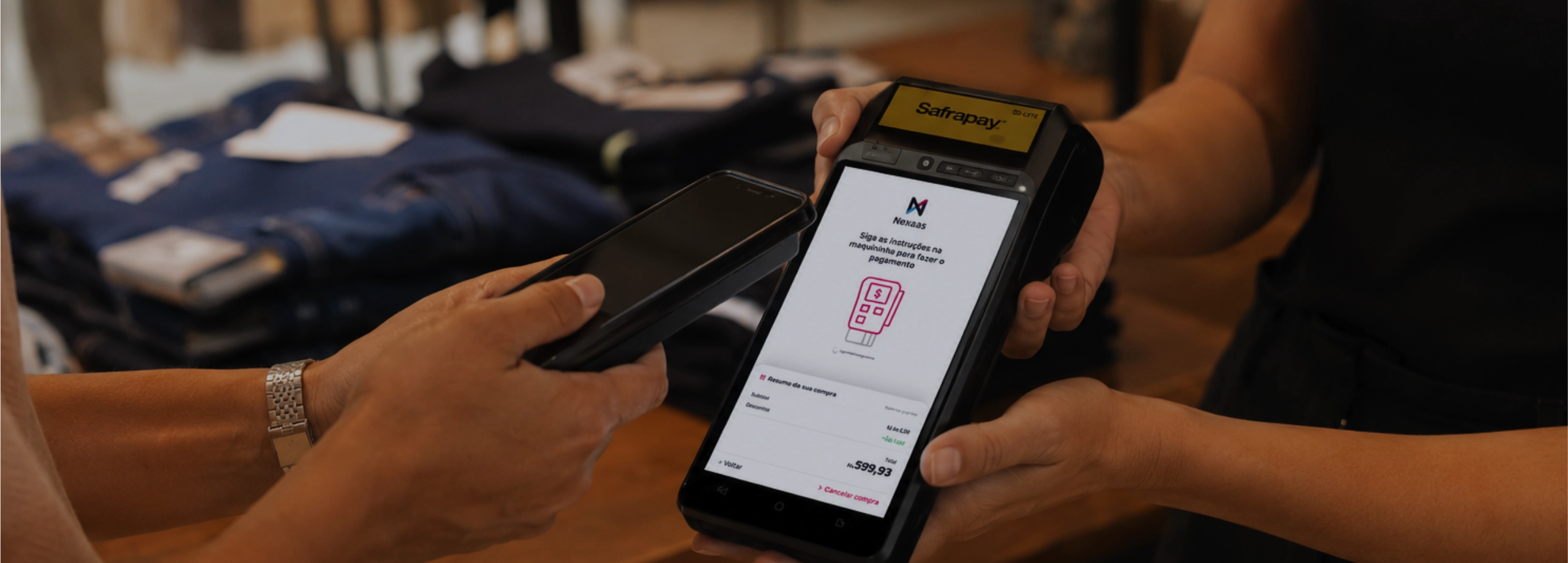 Cliente realiza pagamento por aproximação usando um smartphone em uma maquininha de cartão inteligente segurada por um vendedor.