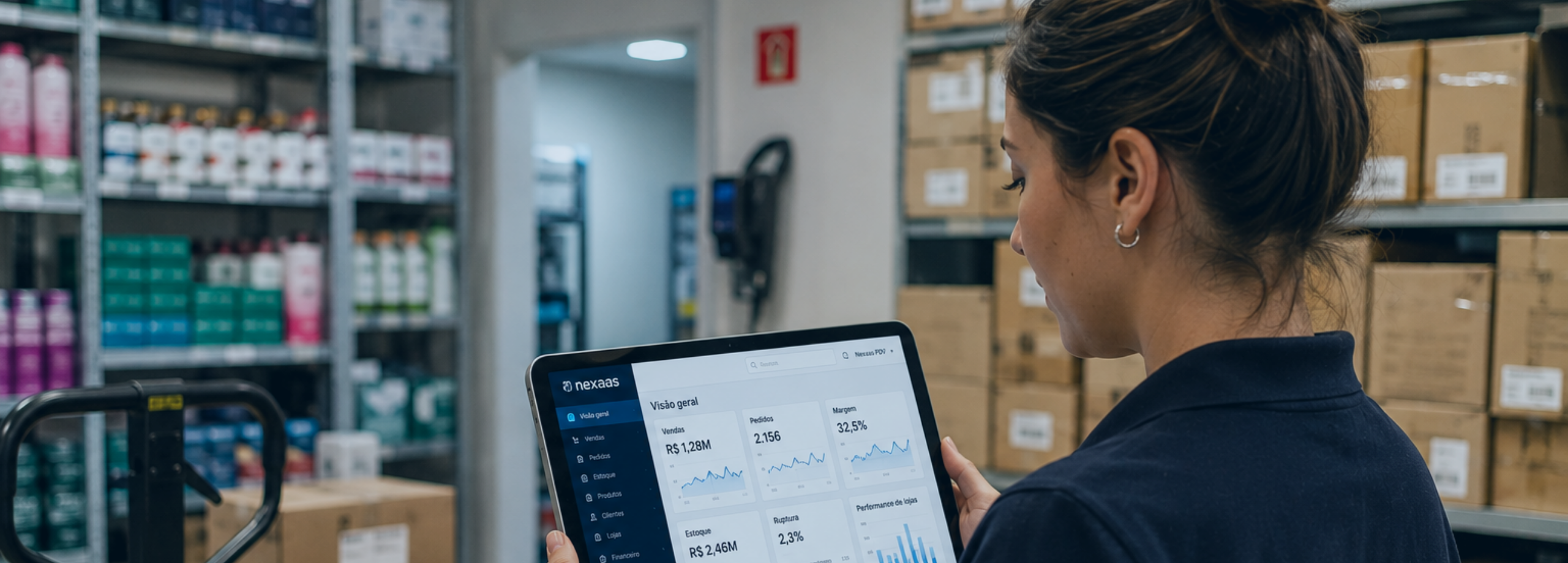 Uma mulher segura um tablet com gráficos e dados dentro de um estoque cheio de mercadorias.