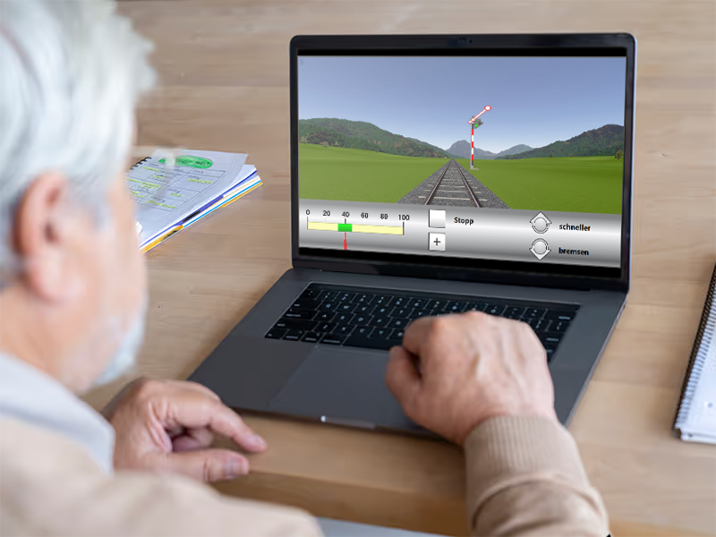 Patient nutzt das alte  RehaCom®-Rehabilitationstraining GEAZ am Laptop, Hände am Laptop auf einem Schreibtisch