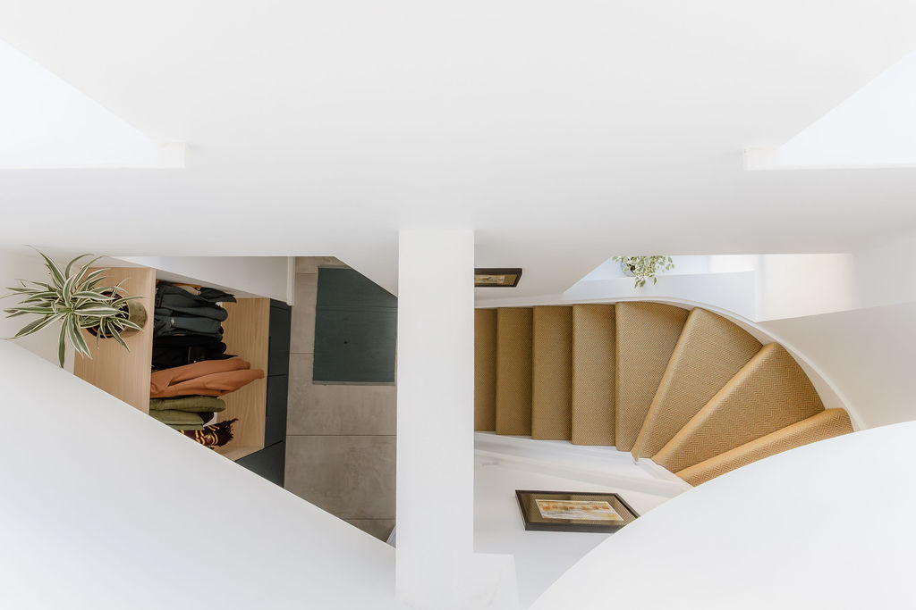 Curved staircase within a two-storey extension, with white walls and daylight from above