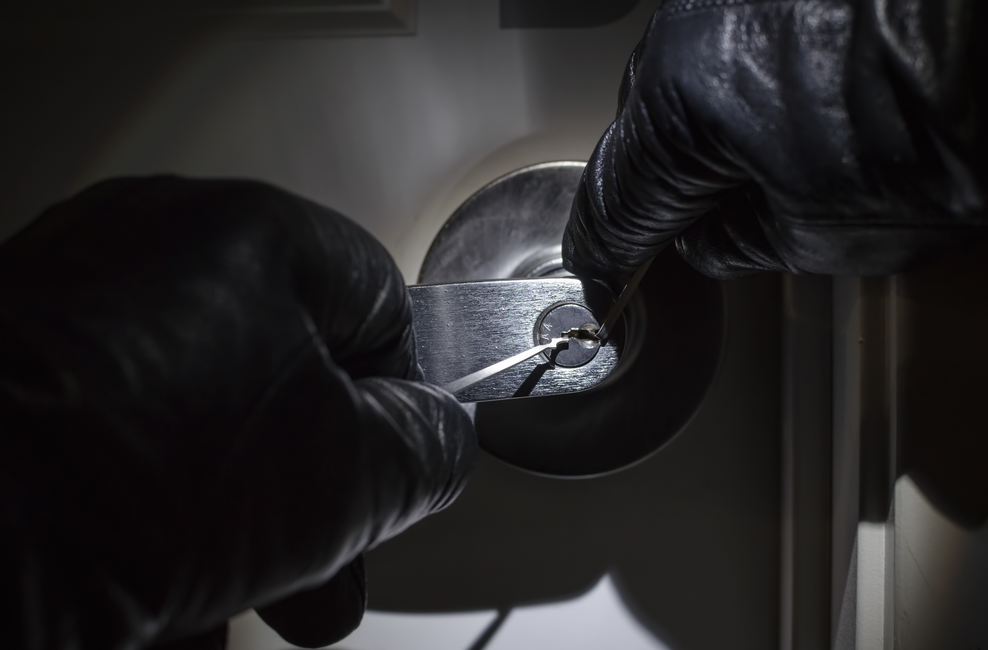 Thief lock picking a door to break into a car dealership., image