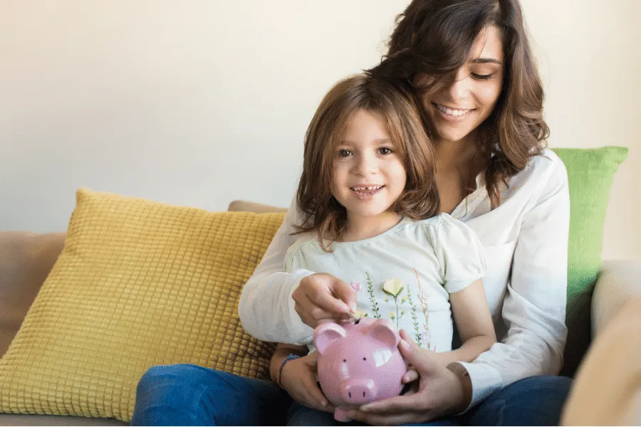 Mother and Daughter saving into a piggy bank