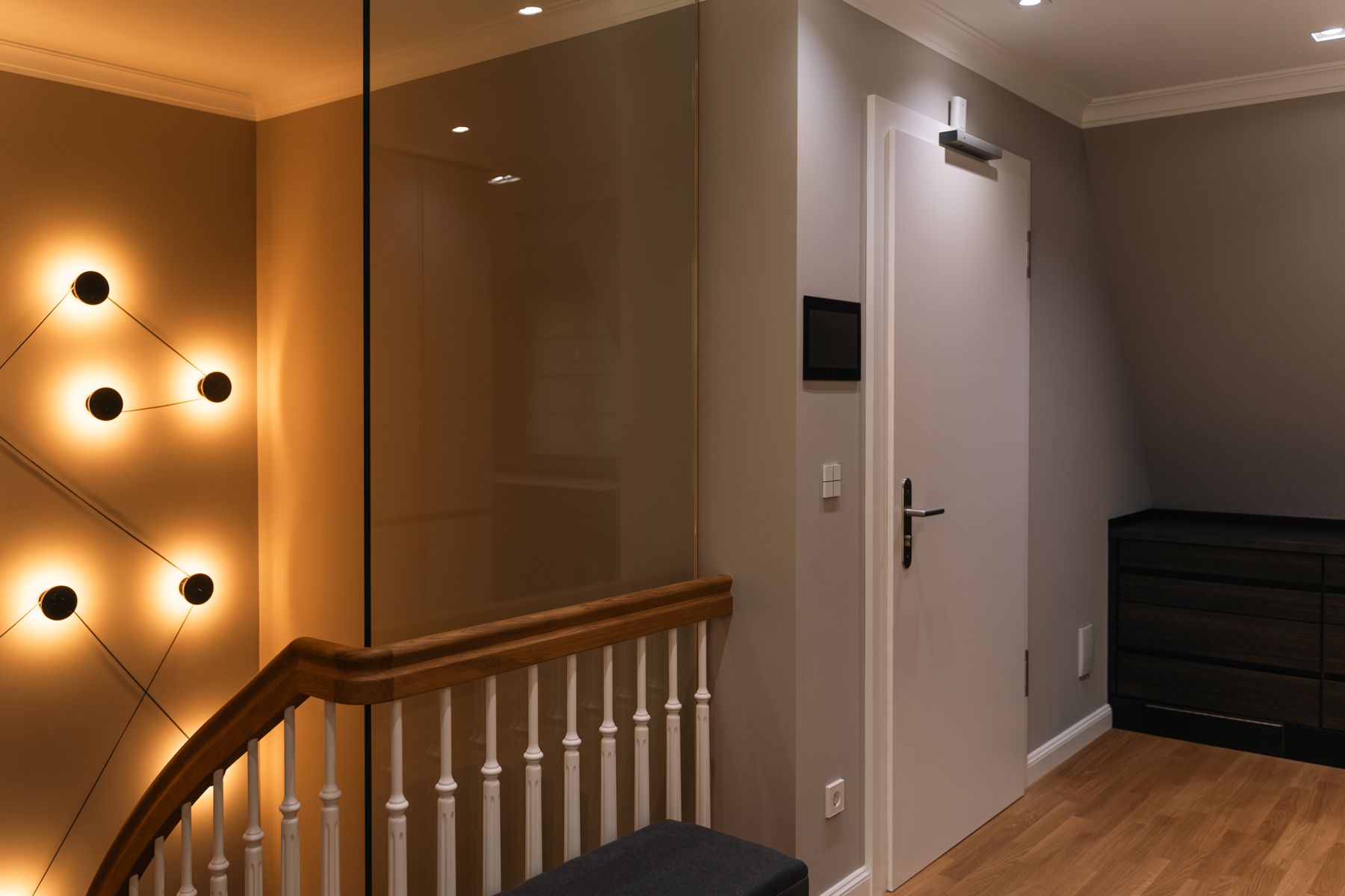 Flur mit Lichtinstallation aus Wandleuchten, Touchpanel und automatischem Türantrieb