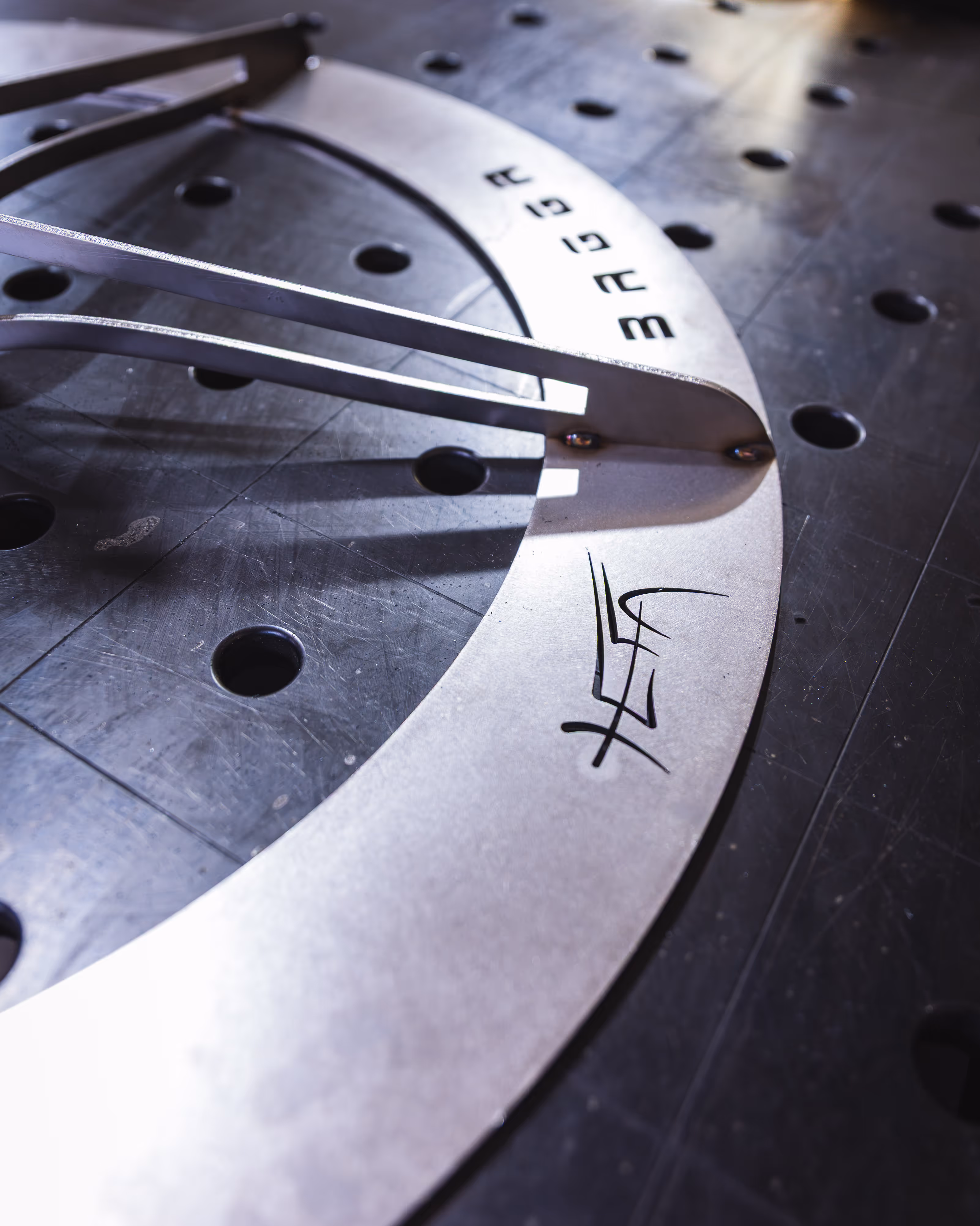 Nahaufnahme des Standfußes aus Edelstahl auf einer perforierten schwarzen Oberfläche.