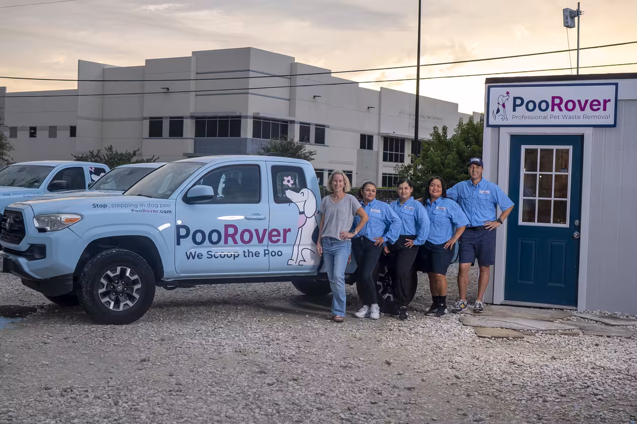 Five people standing beside a PooRover branded truck and office, promoting professional pet waste removal.