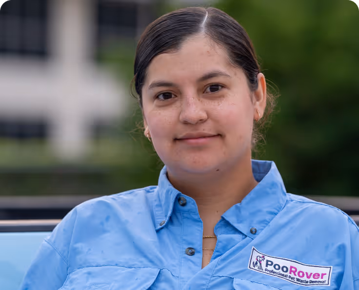 Woman wearing a light blue shirt with PooRover logo, standing outdoors with a soft-focused background.