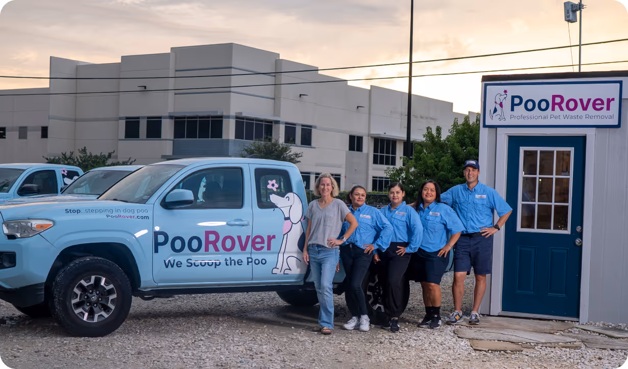 Five PooRover staff members standing beside a branded truck and office building for professional pet waste removal service.