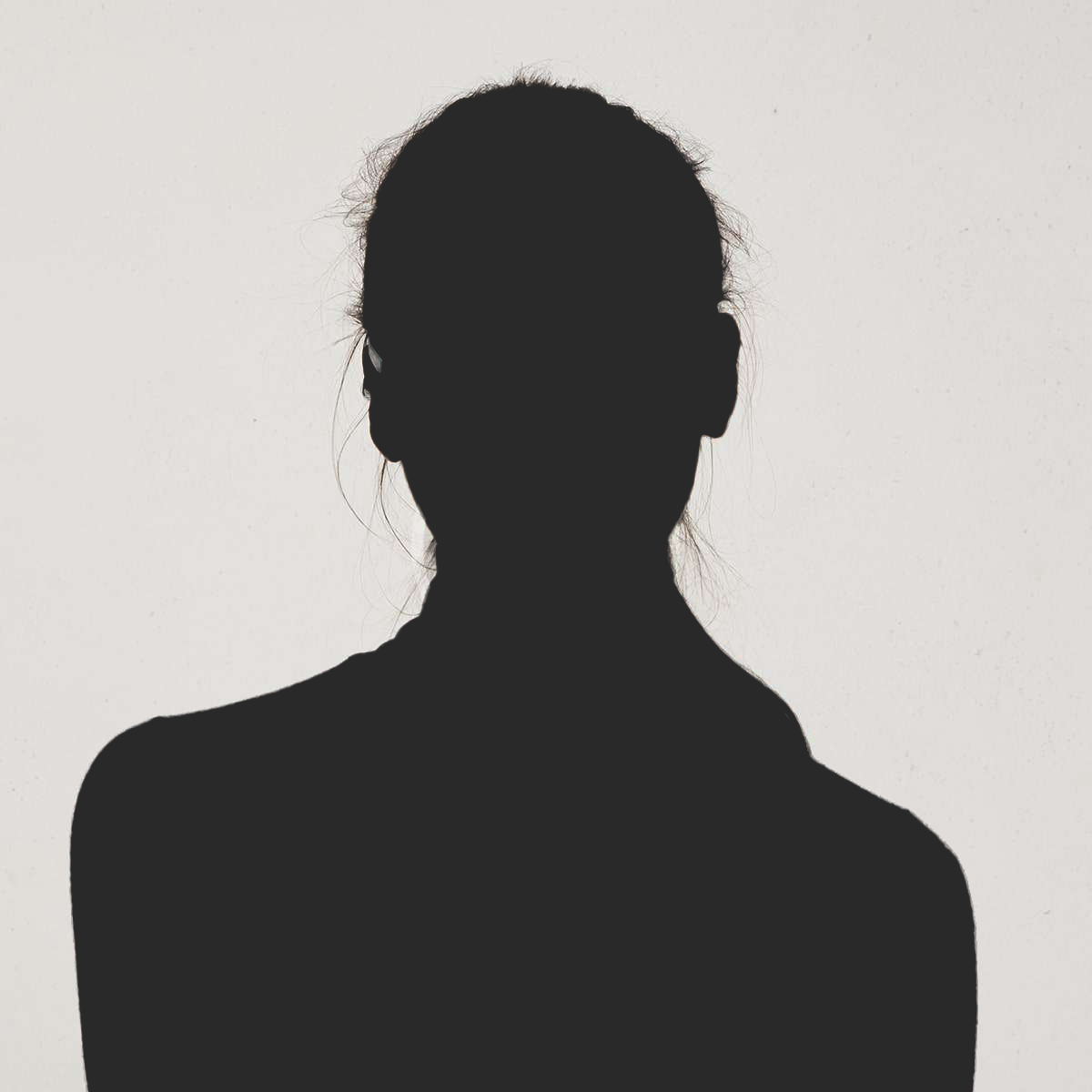 Silhouette of a person with hair tied back against a plain light background.