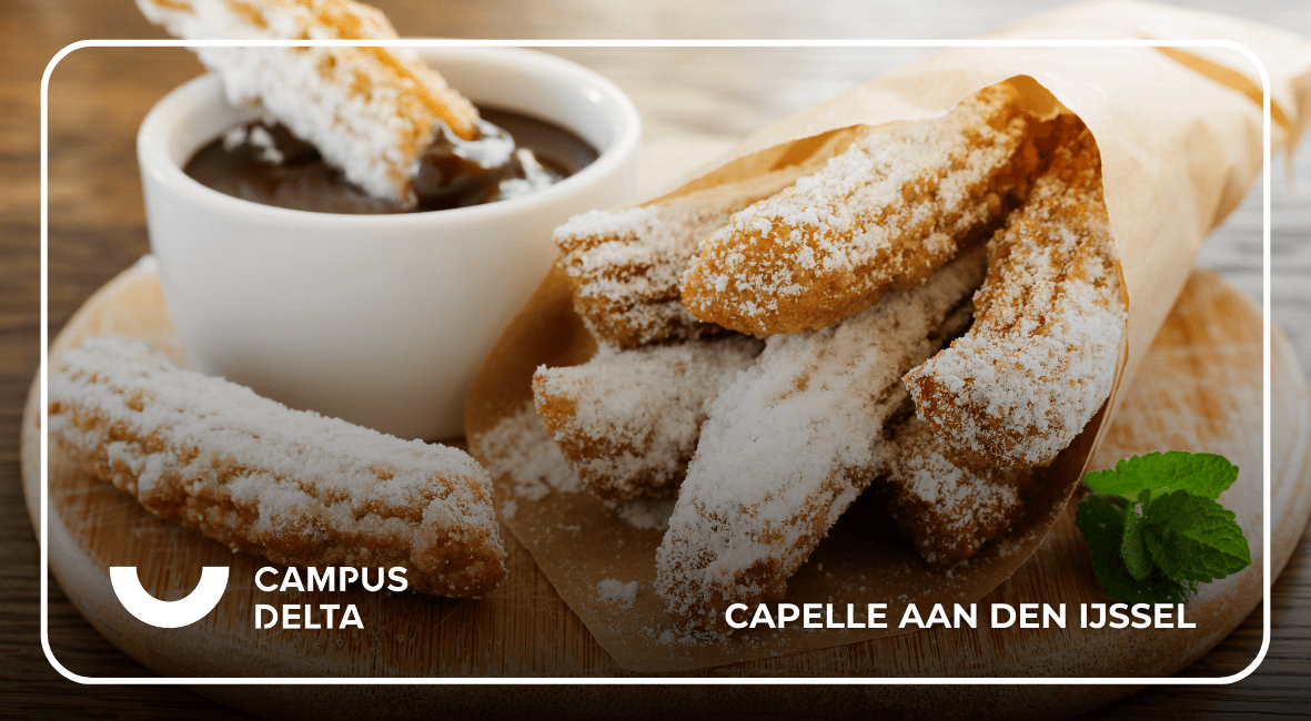 Churros met poedersuiker naast een kopje chocoladesaus op een houten plank bij Campus Delta in Capelle aan den IJssel