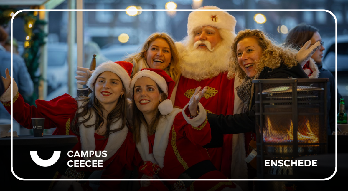 Mensen verkleed als kerstvrouwen poseren lachend met de kerstman bij Campus CeeCee in Enschede tijdens de kerstmarkt