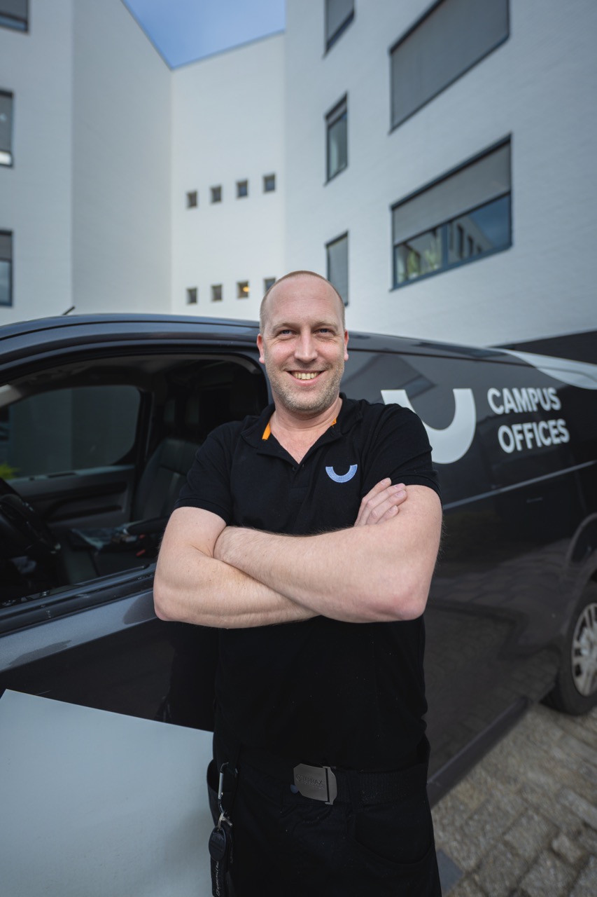 Richard Nijboer, leunt met zijn armen over elkaar voor een Campus Offices busje