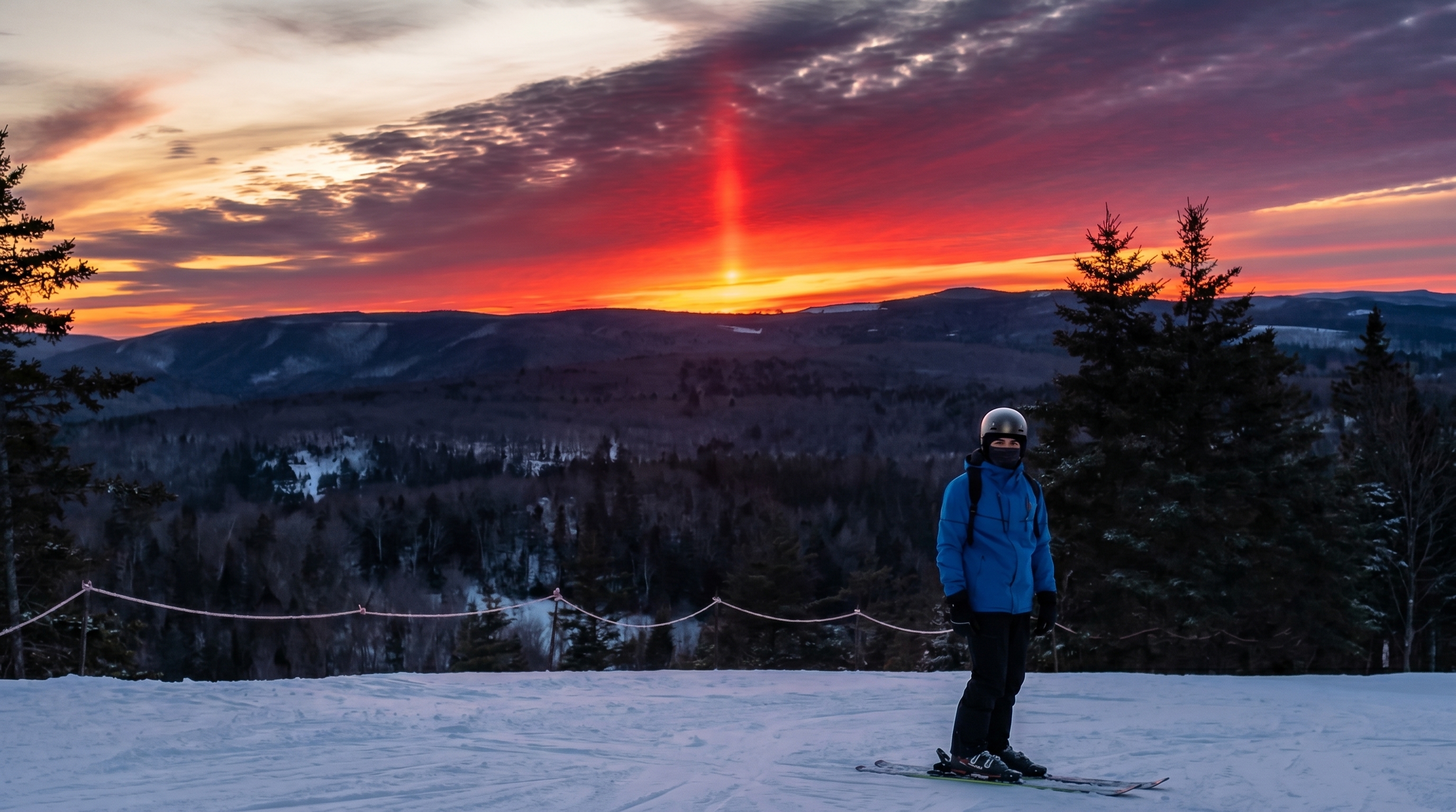 Meet Chaudhari on a ski slope at sunset overlooking snow-covered mountains and forest