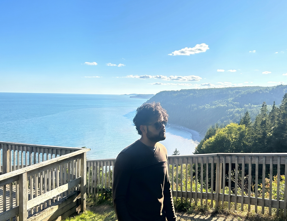 Meet Chaudhari taking in a coastal ocean view from a wooden lookout deck in New Brunswick
