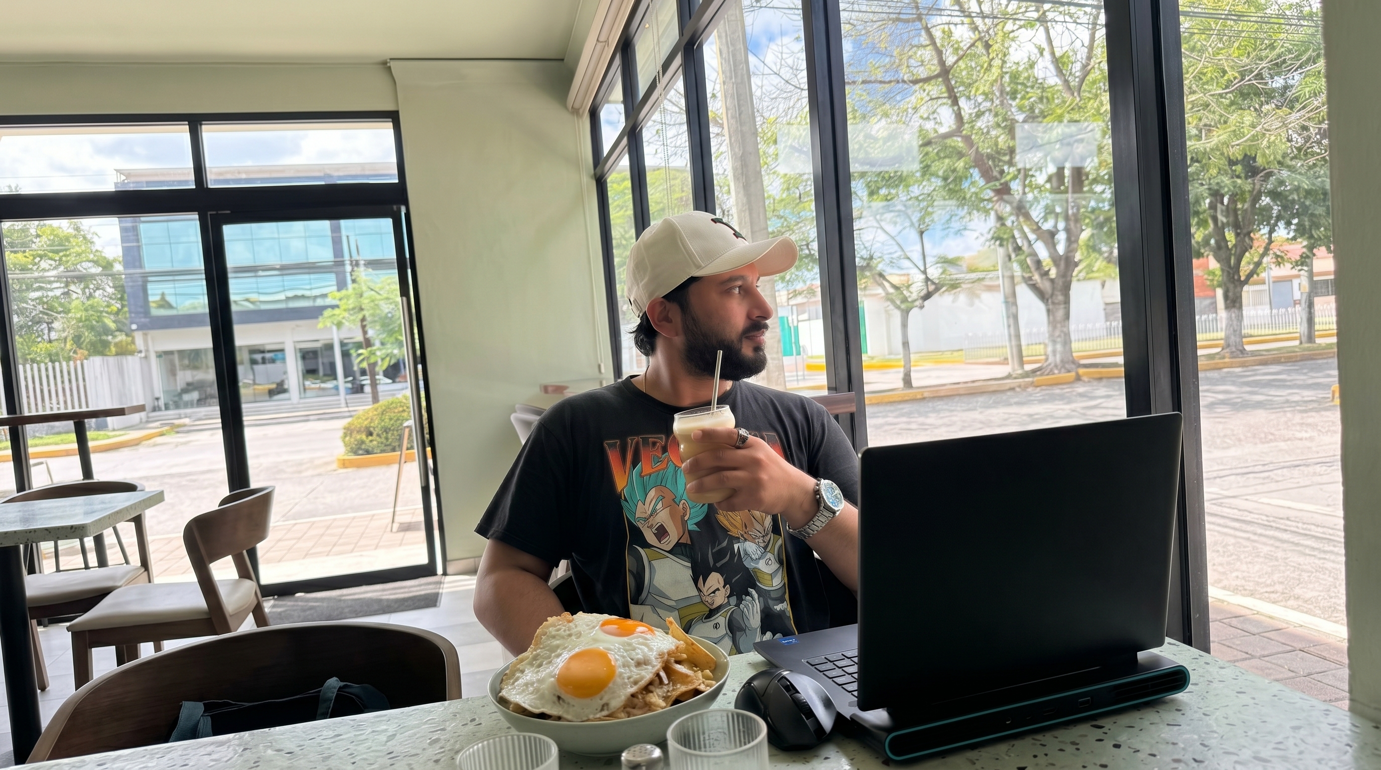Nikhil Sharma working remotely from a sunlit café with a laptop and local breakfast, showcasing DigiBenders' remote-first culture