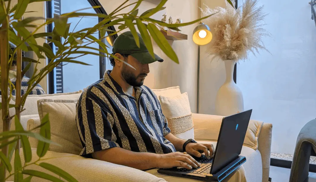 Nikhil Sharma, founder of DigiBenders, at his desk with software architecture diagrams on a whiteboard and code on dual monitors