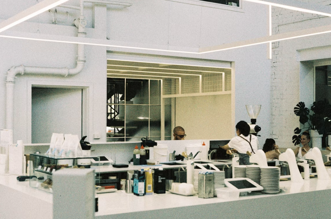 Staff behind a sleek counter with POS systems, kitchen gear, and food prep items