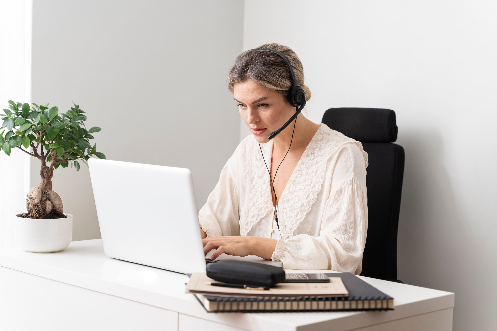 Focused woman working from home in Moncton, NB, using a laptop and headset.