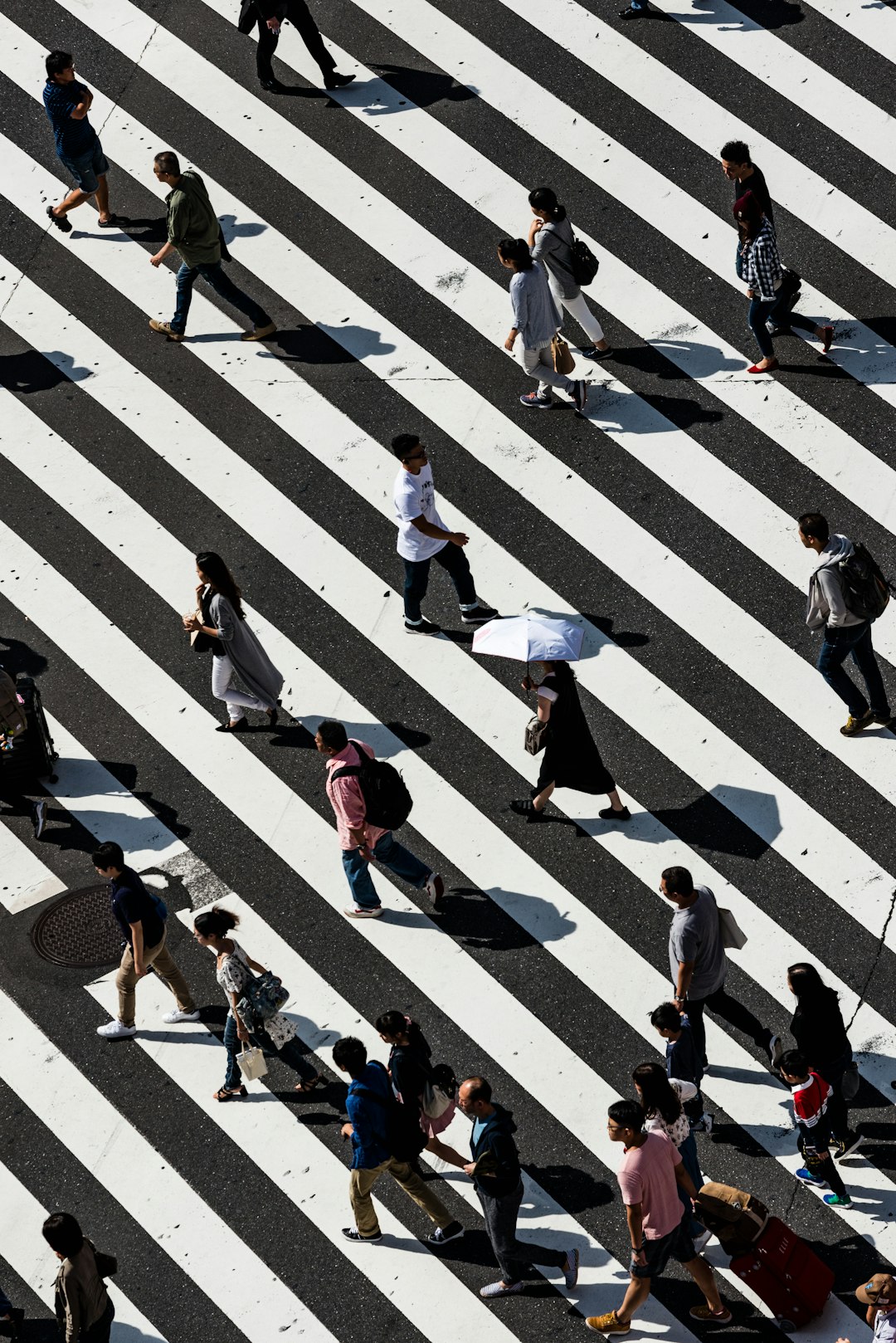 Aerial view of people walking across a busy zebra crossing