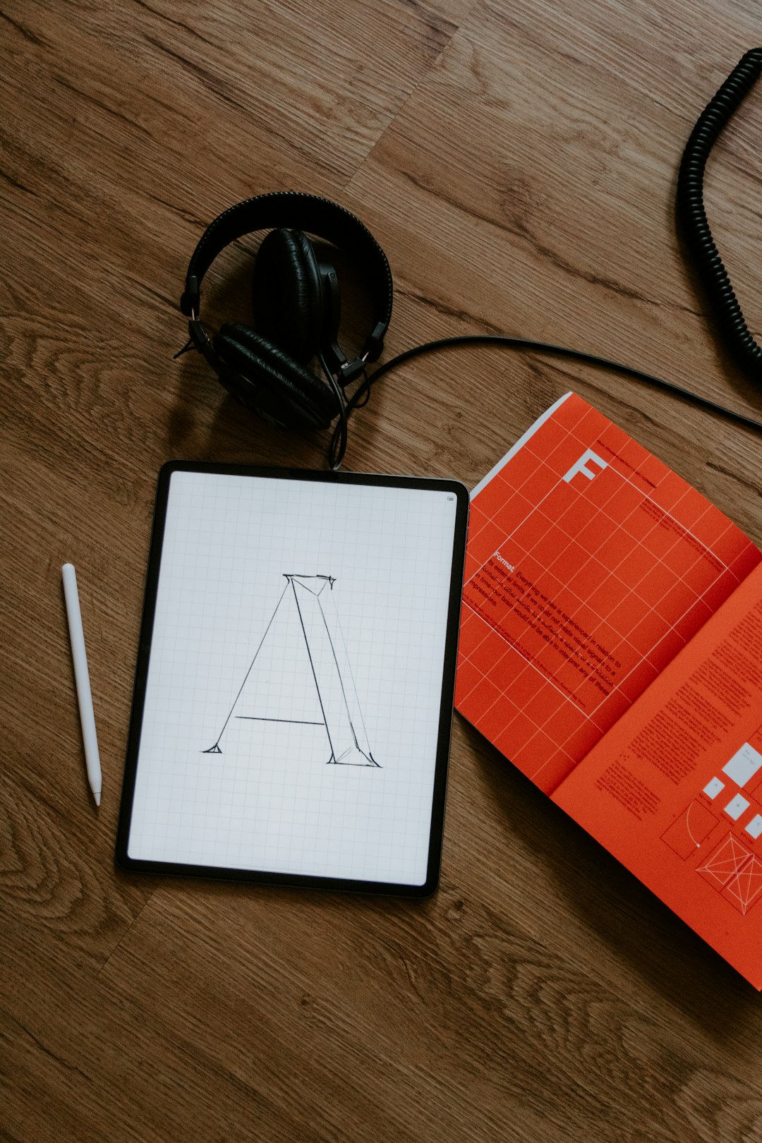 Typography sketch on tablet with design magazine and headphones
