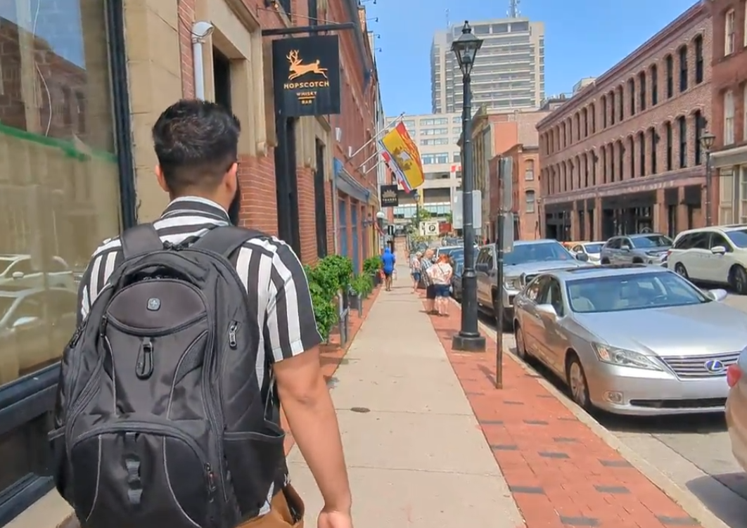 Person walking into Hopscotch Whisky Bar in Uptown Saint John, New Brunswick on a sunny day.
